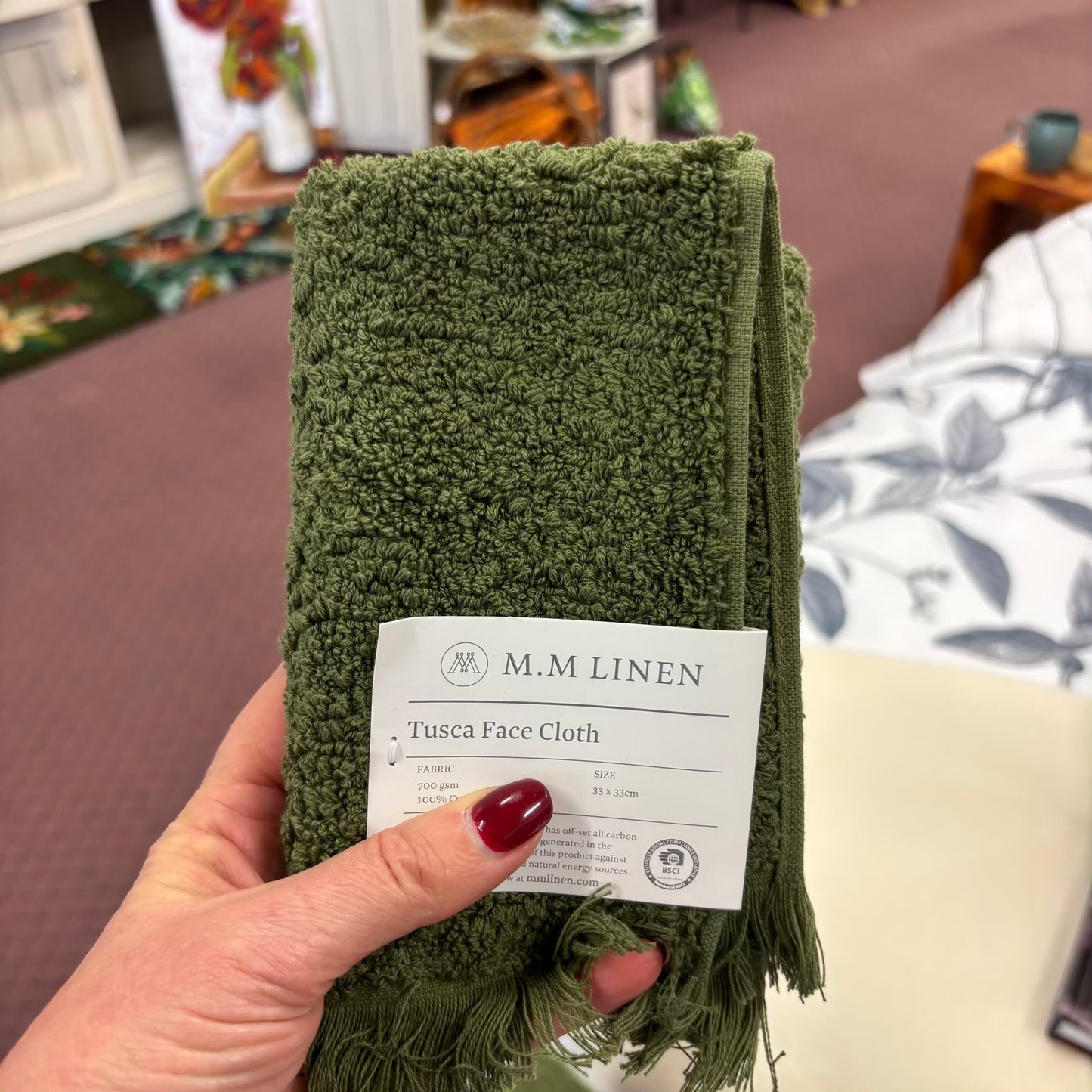 Green face cloth with M.M Linen label held by a hand
