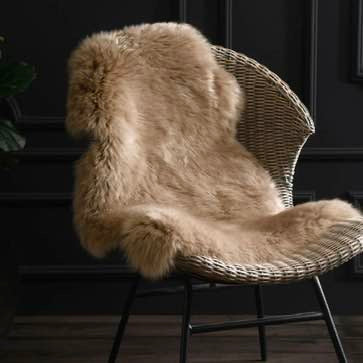 Wicker chair with a Taupe Sheepskin throw draped over it against a dark background