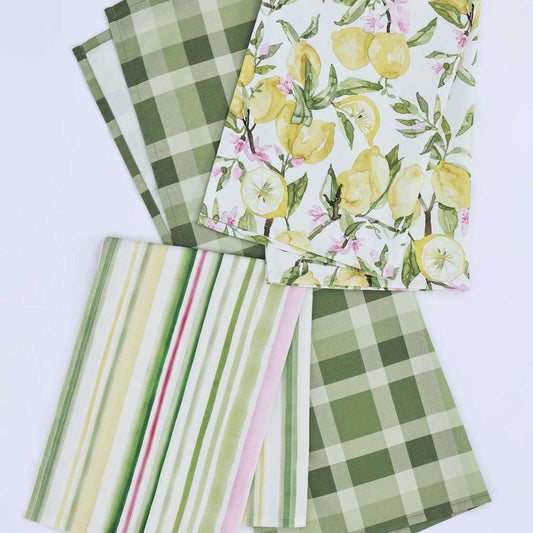 Set of 3 tea towels arranged on a white background, showing different patterns: two green plaid, one green-and-white striped with pink and yellow stripes, and one white with yellow lemons and pink flowers.