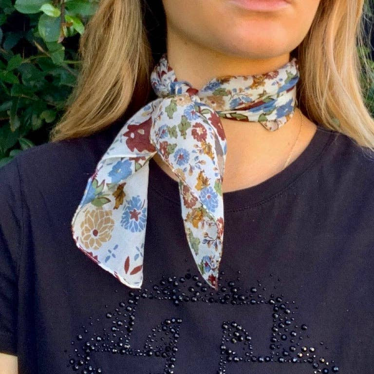 Person wearing a floral neck scarf on a dark shirt with decorative elements