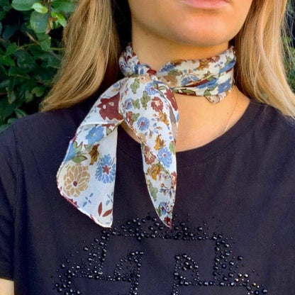 Person wearing a floral neck scarf on a dark shirt with decorative elements