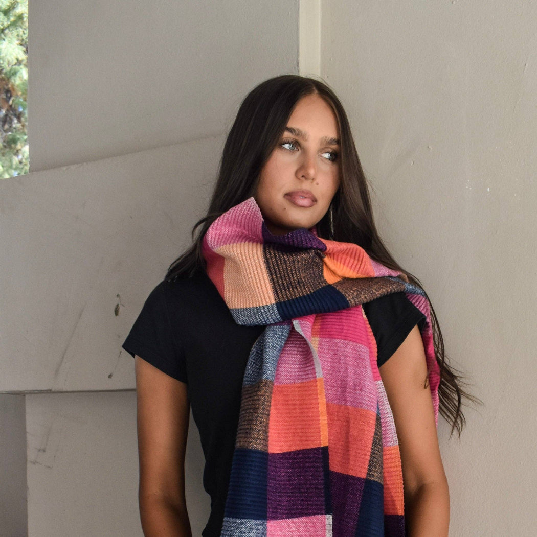 Woman wearing a colorful checkered scarf against a neutral background