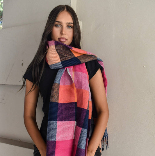 Woman wearing a colorful plaid scarf against a neutral background