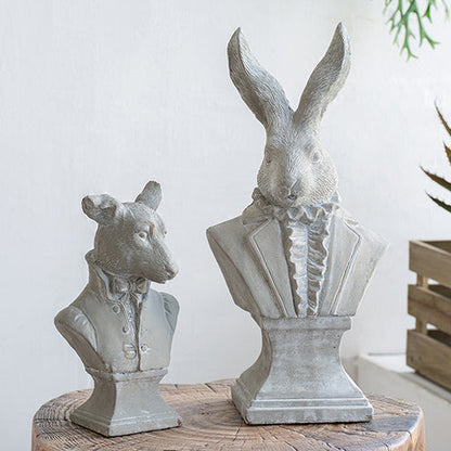 Decorative animal busts on a wooden stump with a white wall and plants in the background