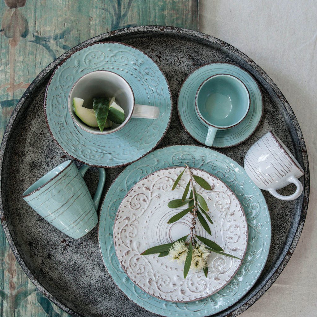 Set of ceramic mugs and plates on a dark tray with decorative elements.
