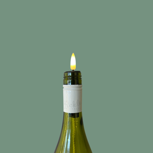 Wine bottle with a lit candle on a green background