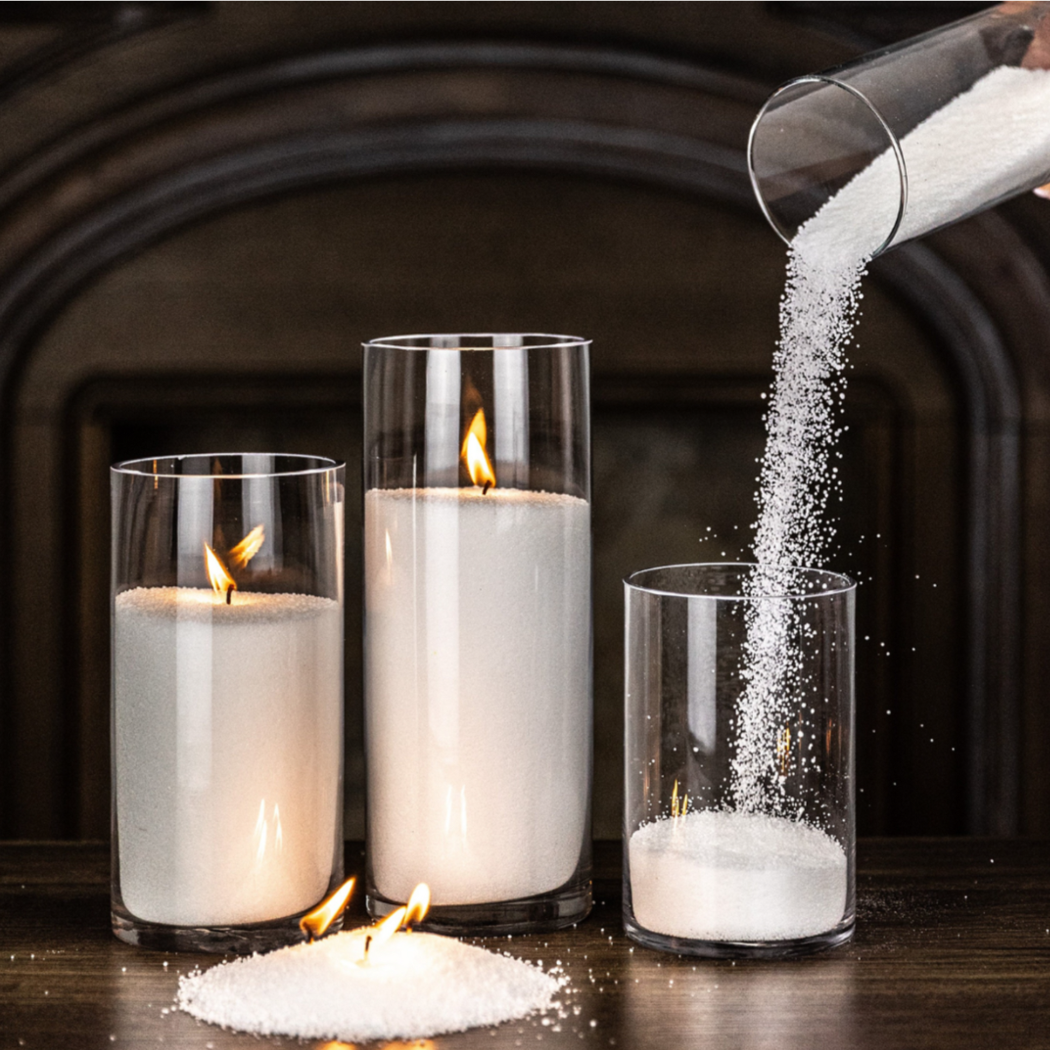 Candle holders with burning candles and a person pouring white powder into a glass.