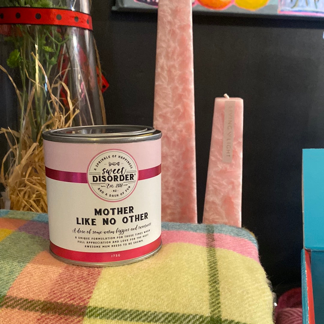 A canister labeled 'Sweet Disorder' with 'Mother Like No Other' written on it, placed on a colorful checkered surface, likely containing candy or confectionary treats.