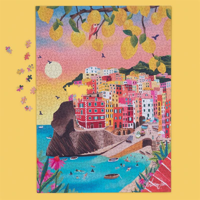 A colorful jigsaw puzzle depicting a coastal town with bright buildings, boats in the water, birds, and yellow lemons hanging from branches, shown on a yellow background with a few loose puzzle pieces nearby.