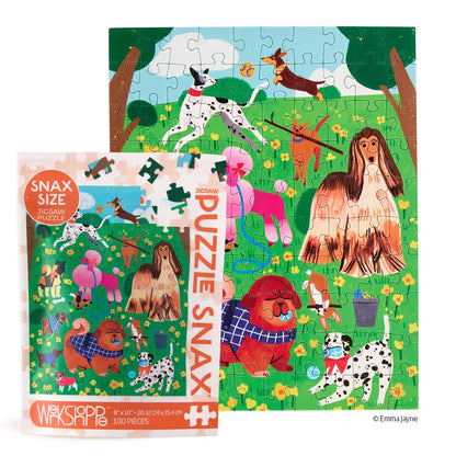 A colorful dog-themed jigsaw puzzle and its retail box shown on a white background. The puzzle features playful dogs in a grassy field with trees, and the box reads 'SNAX SIZE PUZZLE PUZZLE SNAX' with '200 PIECES' at the bottom.