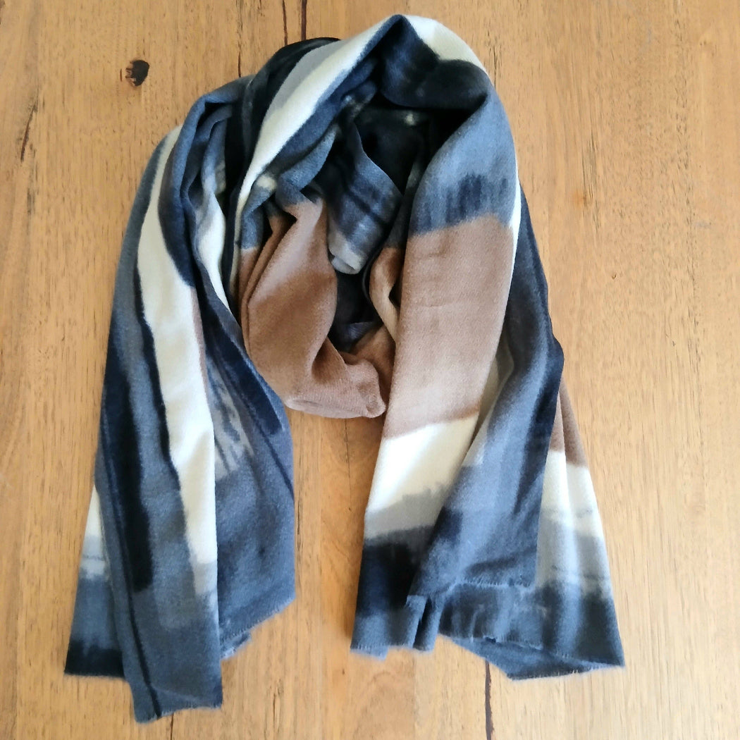 Colorful scarf with black, beige, and brown tones on a wooden surface