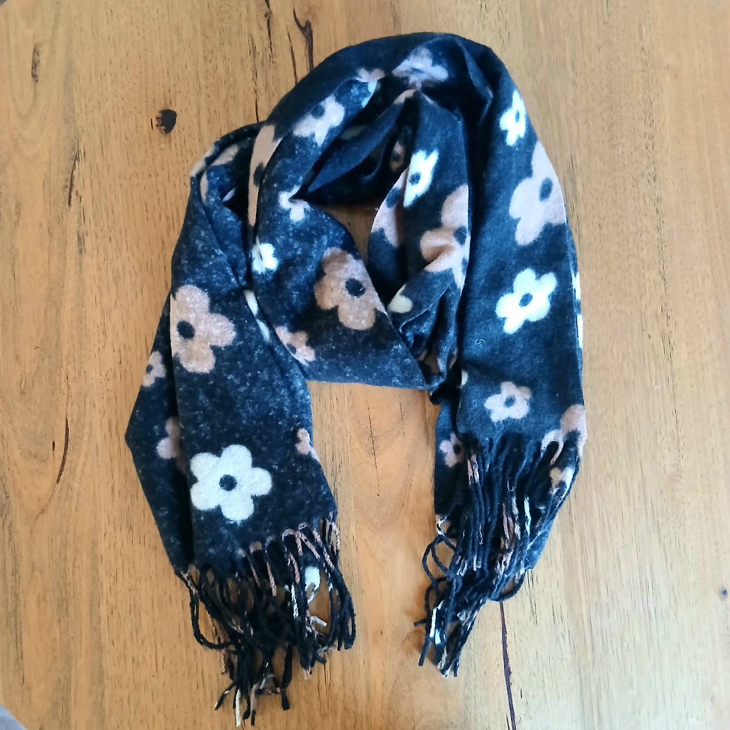 Floral patterned scarf with black tassels on a wooden surface