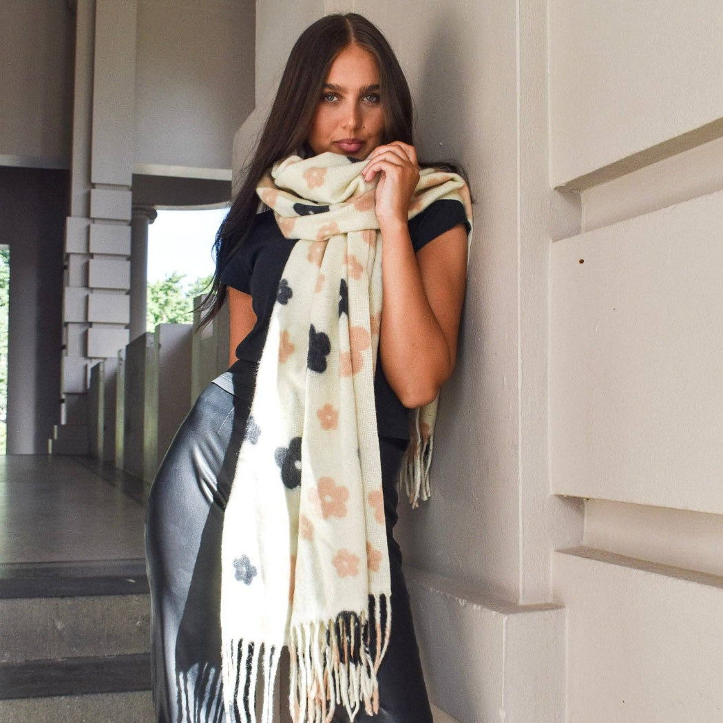 Woman wearing a patterned scarf leaning against a building.