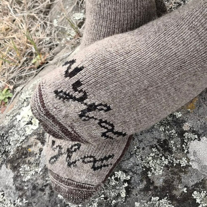 A close-up of a pair of brown casual socks with the Wyld logo visible, placed on a natural stone surface.